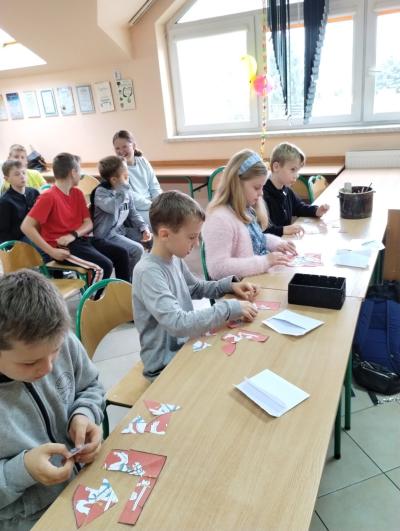 Czterech uczniów z klasy 3 układa puzzle przedstawiające herb Litwy