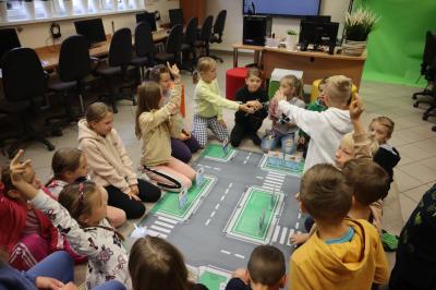 Uczniowie klasy 3a siedzą wokół maty przedstawiającej plan miasta.