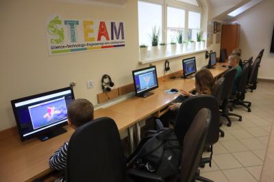 Uczniowie siedzą przy komputerach, uczą się programowania na stronie code.org.