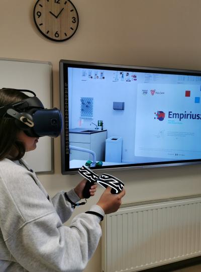 Uczennica w goglach VR i kontrolerach przeprowadza doświadczenie chemiczne