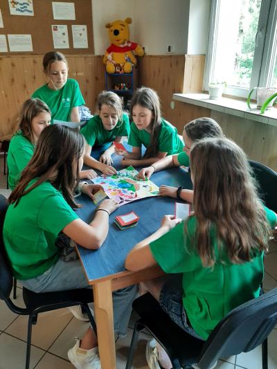 członkowie klubu ekologa w zielonych koszulkach grają w grę ekologiczną wymyśloną i wykonaną przez uczennicę klasy 4a