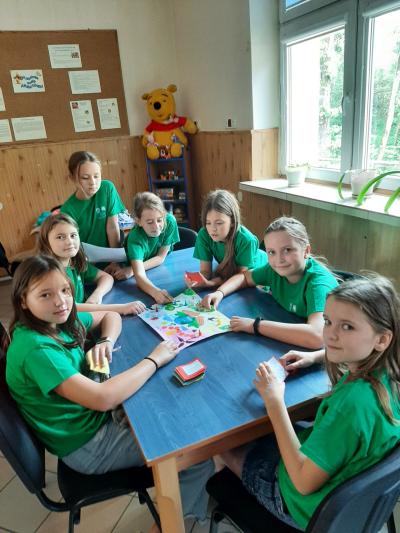 członkowie klubu ekologa w zielonych koszulkach grają w grę ekologiczną wymyśloną i wykonaną przez uczennicę klasy 4a