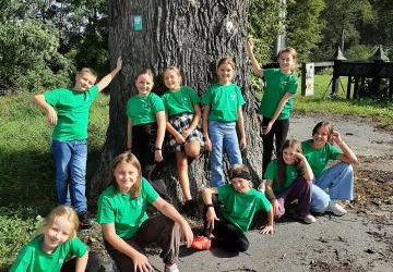 członkowie klubu ekologa podczas zajęć w terenie, uczniowie mają na sobie zielone koszulki, otaczają stary dąb - pomnik przyrody