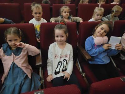 Przedszkolaki siedza w kinie czekając na seans filmowy.