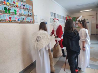 Święty Mikołaj wraz z aniołkami puka do drzwi aby adwiedzić uczniów w klasie.