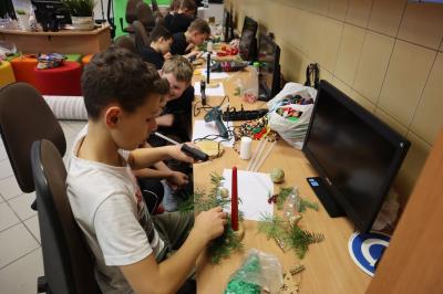 Uczniowie klasy VIb wykonuja na stolikach stroiki bożonarodzeniowe z pienków drewnianych, gałązek jodły, bombek, szyszek, orzechów.
