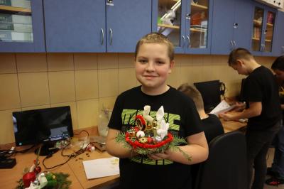 Uczeń klasy VIb prezentuje własnoręcznie wykonany stroik bożonarodzeniowy.