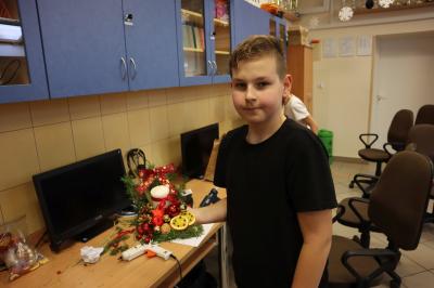 Uczeń klasy VIb prezentuje własnoręcznie wykonany stroik bożonarodzeniowy.