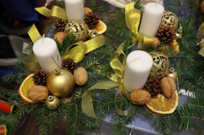 Stroiki bożonarodzeniowe wykonane z pieńka drewnianego, świecy, gałązek jodłowych, szyszek, orzechów i bombek.
