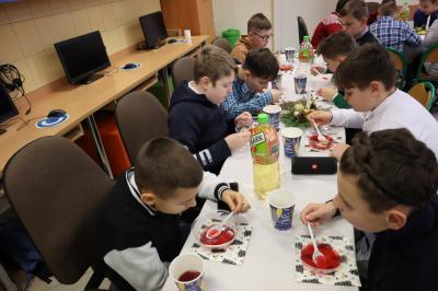 Dzieci siedzą przy stole i spożywają potrawy wigilijne.