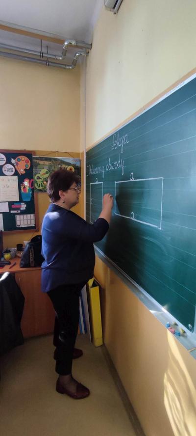 Nauczyciel  przy tablicy w trakcie objaśnień matematycznych