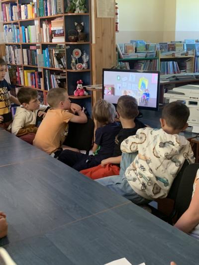 Dzieci ogladają film animowany na monitorze o tym jak postaje książka