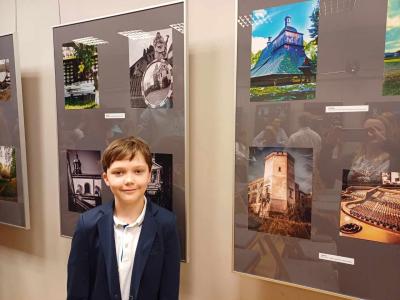 Uczeń Kacper Bogdan . W tle prace fotograficzne