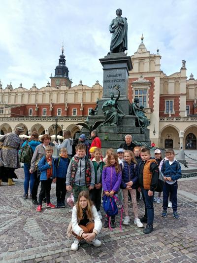 dzieci stoją pod pomnikiem Adama Mickiewicza