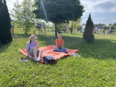 dwie dziewczynki siedzą na trawie na kocu