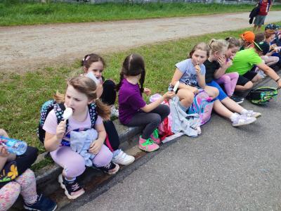 Dzieci siedza na krawężniku i jedzą lody