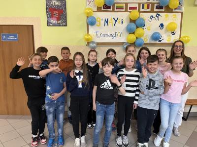 uczniowie z klasy 4 stoją na korytarzu z nauczycielem w dniu święta programu eTwinning.