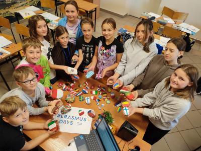 Grupa uczniów prezentuje flagi wykonane na kamykach.