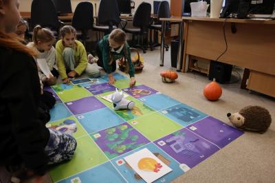 Uczniowie programują robota Photon aby pokonał jesienną trasę na macie edukacyjnej.