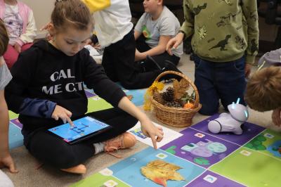 Uczniowie programują robota Photon aby pokonał jesienną trasę na macie edukacyjnej.