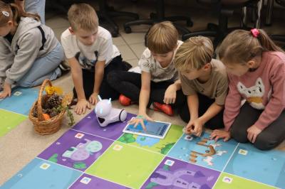 Uczniowie programują robota Photon aby pokonał jesienną trasę na macie edukacyjnej.