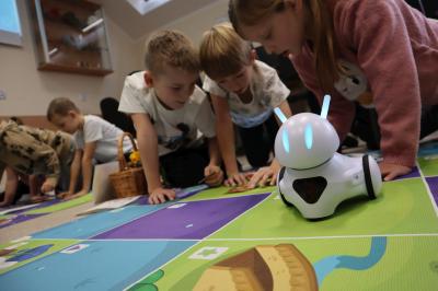 Uczniowie programują robota Photon aby pokonał jesienną trasę na macie edukacyjnej.