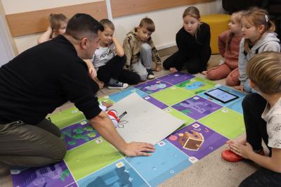 Nauczyciel instruuje uczniów jak obsłużyć robota z uchwytem na mazak