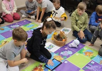 Uczniowie programują robota Photon aby pokonał jesienną trasę na macie edukacyjnej.