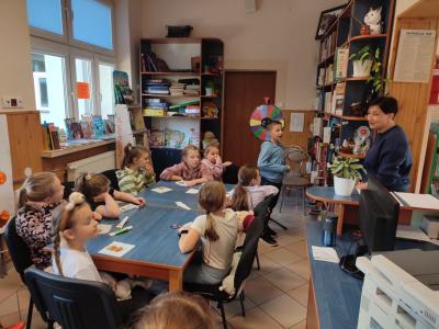 Wokół siedzą przy stolikach w bibliotece.