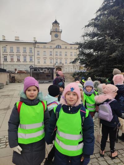 Dziewczynki w kamizelkach odblaskowych pozują do zdjęcia.