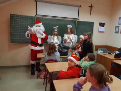 Mikołaj stoi na środku sali i rozdaje upominki