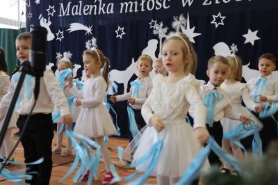 Grupka dzieci tańczy na scenie. Machają błękitnymi wstążkami.