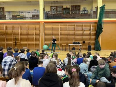 instruktorka fitnessu pokazuje ćwiczenia z użyciem taśmy na hali sportowej