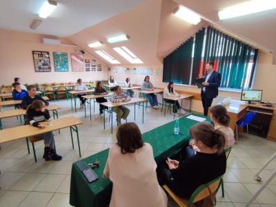 nauczyciel wraz z grupą uczniów siedzących w ławkach