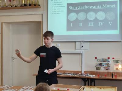 Uczniowie uczestniczą w prelekcji i oglądają kolekcję monet.