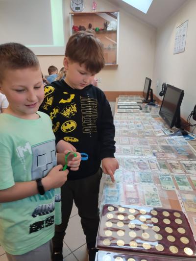Uczniowie uczestniczą w prelekcji i oglądają kolekcję monet.