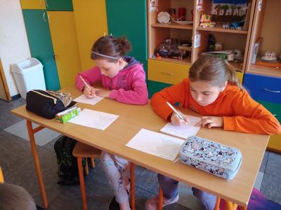 Dzieci biorące udział w szkolnym konkursie kaligrafii przepisują tekst wiersza na kartkę