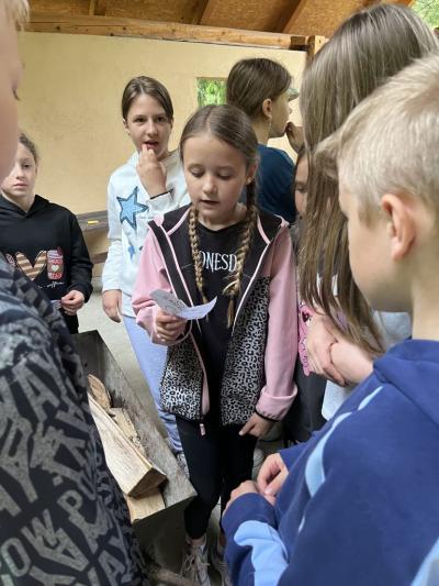 dziewczynka czyta kolejne zadanie do wykonania podczas gry podchody