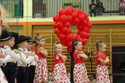 Grupka dzieci w czerwonych strojach  występuje na scenie