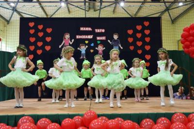 Grupka dzieci w zielonych strojach występuje na scenie