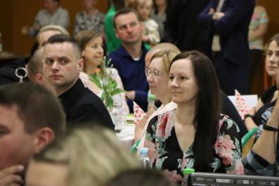 Zaproszeni goscie oglądają występ dzieci, siedzą przy stołach