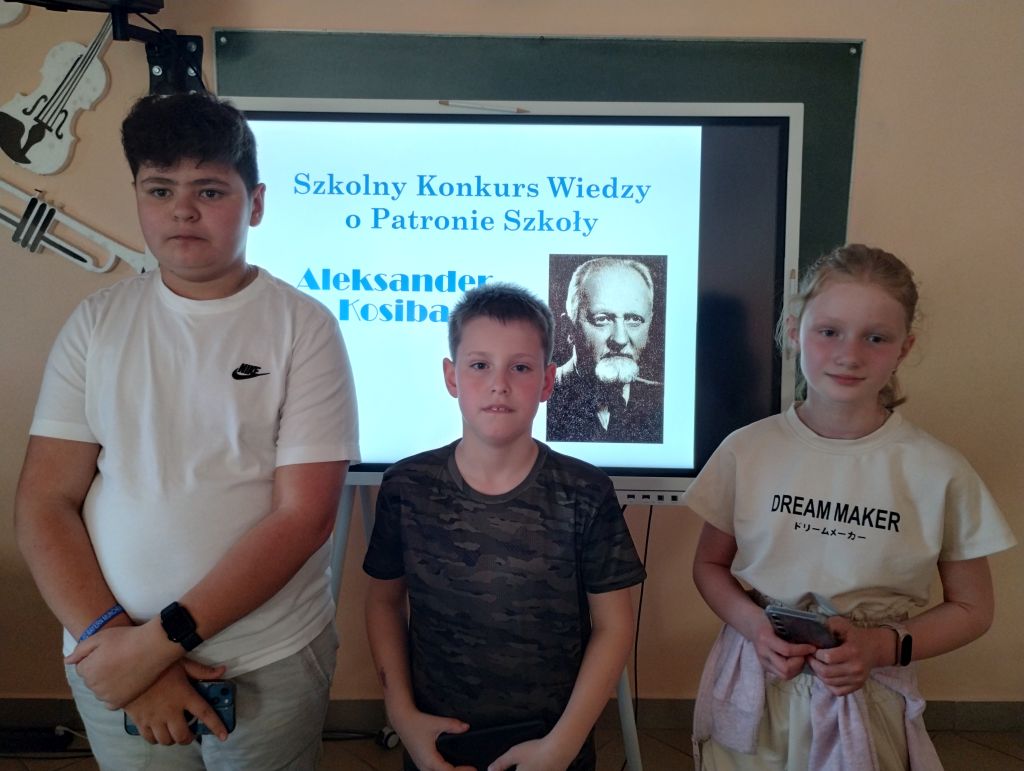 Laureaci konkursu na tle zdjęcia patrona szkoły.