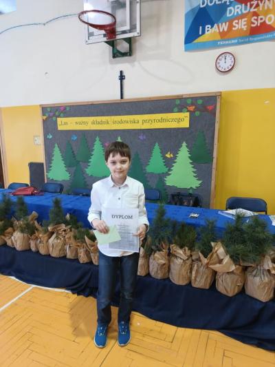 Kacper trzyma w ręku dyplom i nagrodę