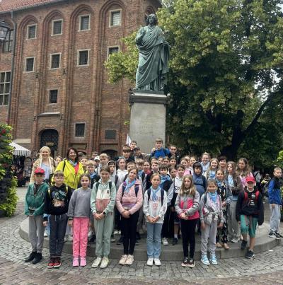 Uczestnicy Zielonej Szkoły pozują do zdjęcia przy pomniku Mikołaja Kopernika w Toruniu.