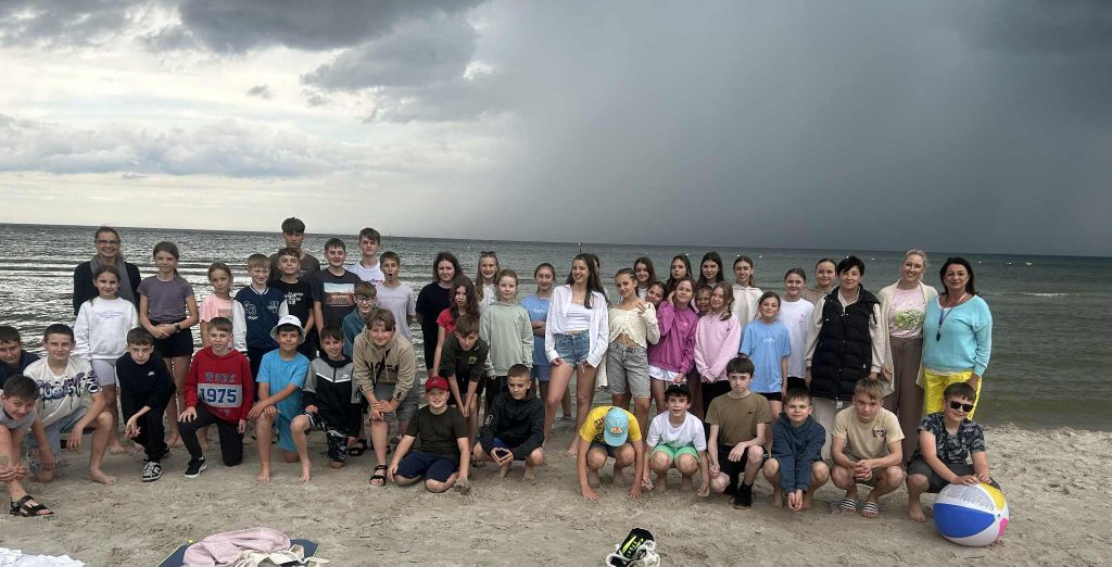 Uczestnicy Zielonej Szkoły pozują do zdjęcia na plaży. Uczestnicy Zielonej Szkoły pozują do zdjęcia na plaży.