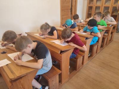 Uczniowie siedzą w ławkach w szkole w Żarnowcu w czasie warsztatów kaligrafii.