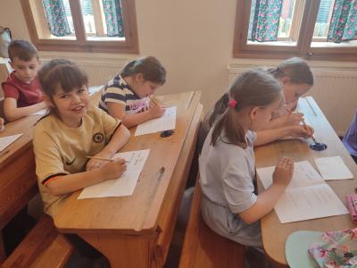 Uczniowie siedzą w ławkach w szkole w Żarnowcu w czasie warsztatów kaligrafii.