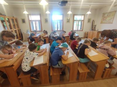 Uczniowie siedzą w ławkach w szkole w Żarnowcu w czasie warsztatów kaligrafii.