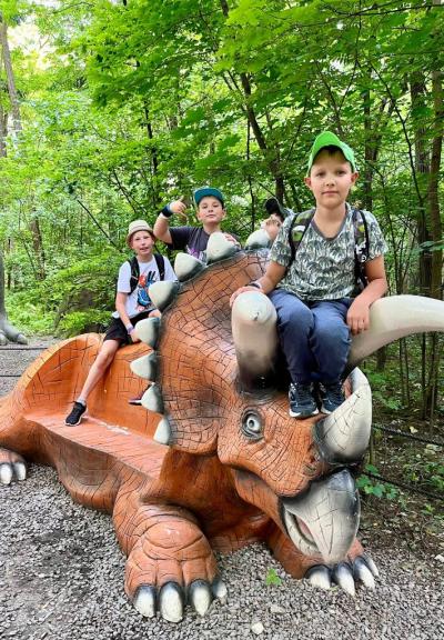 uczniowie siedzą na dinozaurze