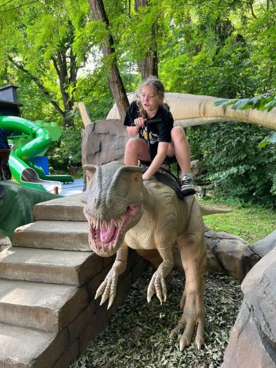 uczennica siedzi na dinozaurze.